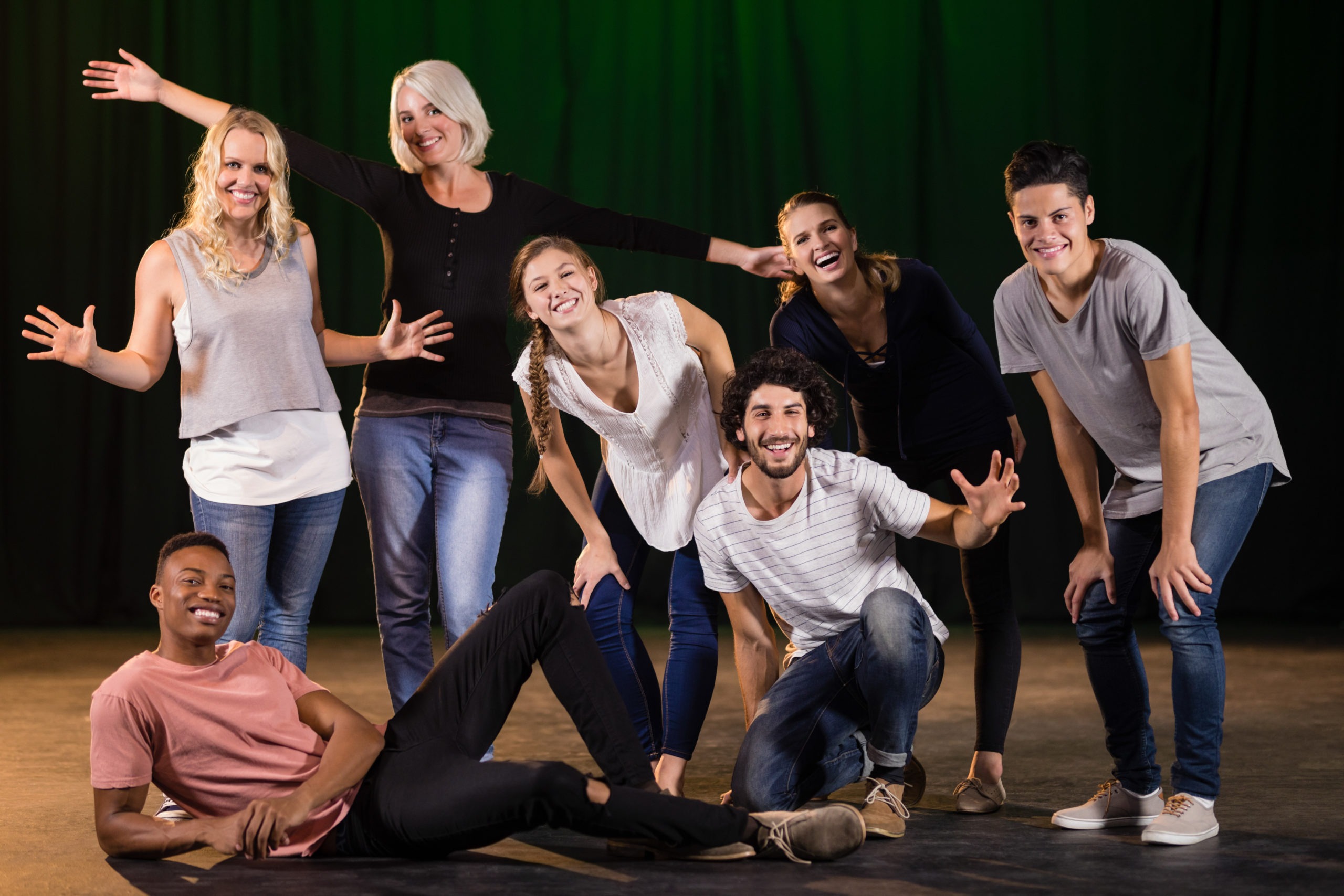 Actors practicing play on stage. A group of people are posing for a picture