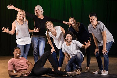 Actors practicing play on stage. A group of people are posing for a picture