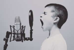 black and white photo of a five year old boy screaming or singing on a studio microphone